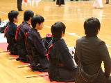 選手たちが正座で座り、試合を見守っている様子